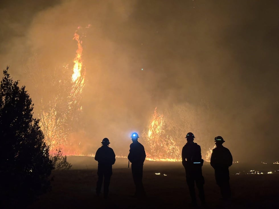 Firefighters stand silhouetted by the Aspen Acres Fire on July 9, 2026.