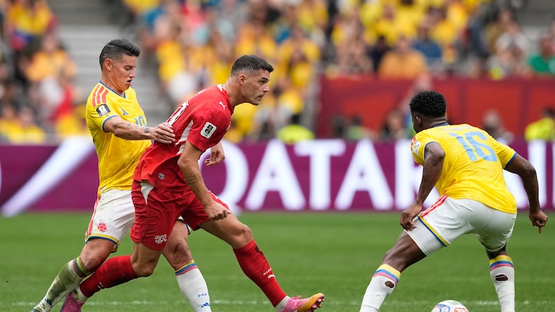 Switzerland's Granit Xhaka, center, tries to get past Colombia's James Rodríguez, left, and...